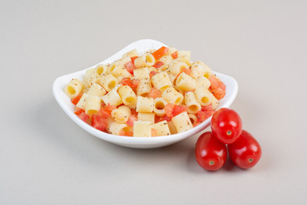 美味开胃的潘恩面食 加香料和番茄片放在白色盘子里通心粉切片晚餐