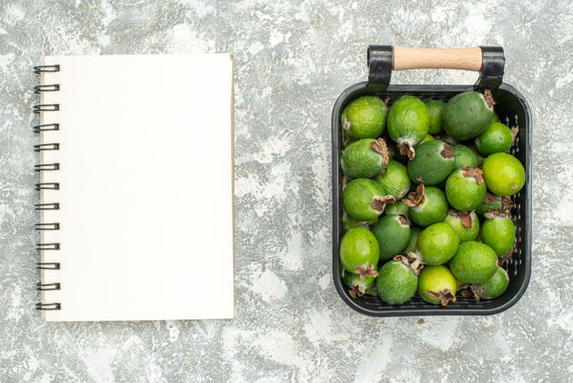 笔记本顶视图新鲜feykhoas在篮子笔记本上的灰色表面多汁鳄梨柑橘