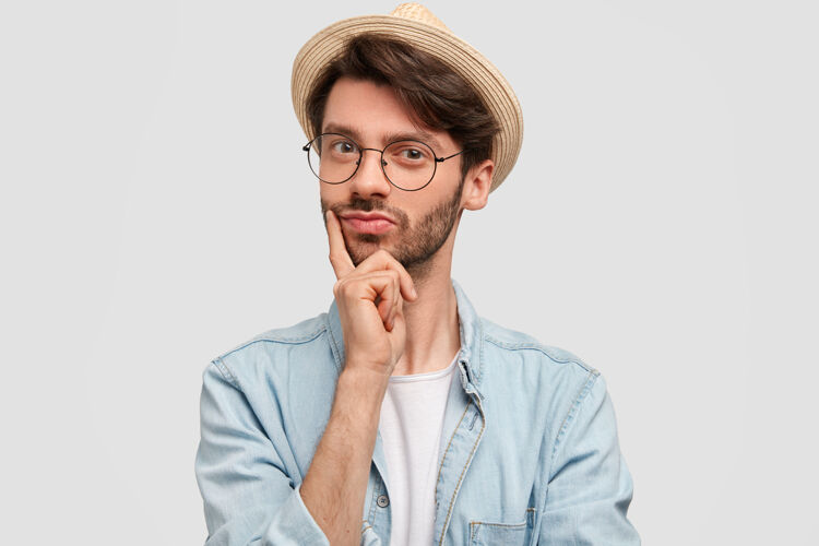 手自信满脸胡须的男性横拍 手指贴在下巴上吸引力帽子眼镜