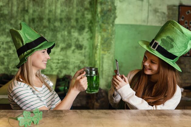 活动快乐的女性朋友一起在酒吧喝酒庆祝圣帕特里克节庆典幸运圣帕特里克盛宴