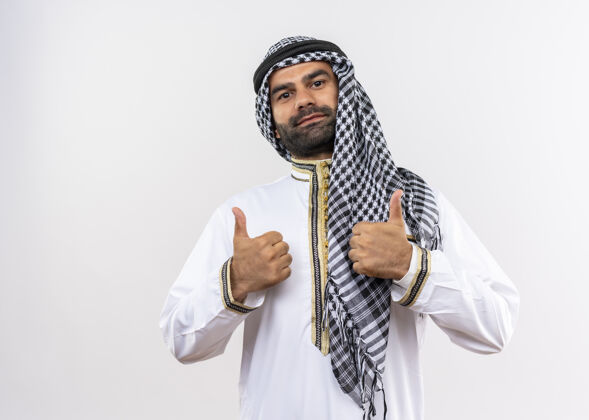 穿身着传统服装的阿拉伯男子微笑着竖起大拇指站在白墙上阿拉伯语男人传统