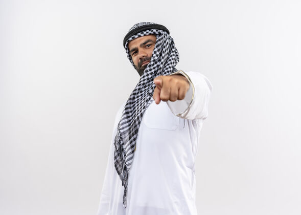 微笑身着传统服装的阿拉伯男子微笑自信地用食指指着白色的墙壁传统阿拉伯语自信
