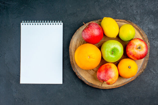苹果俯视图苹果柠檬橘子木板笔记本在黑暗的表面桃笔记本柑橘
