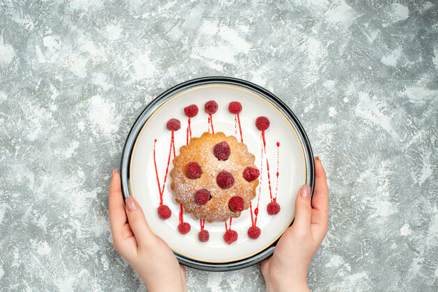 椭圆形俯瞰浆果蛋糕上的白色椭圆形盘子在女性手上的灰色表面自由空间视图盘子玻璃