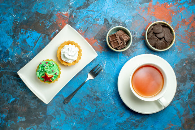 巧克力俯视图一杯茶 蛋糕放在盘子里 巧克力放在蓝红色的小碗里饮料视图碗