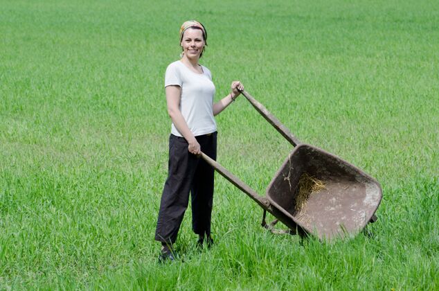 环境自信的女性在农场里用手推车工作工业公园微笑