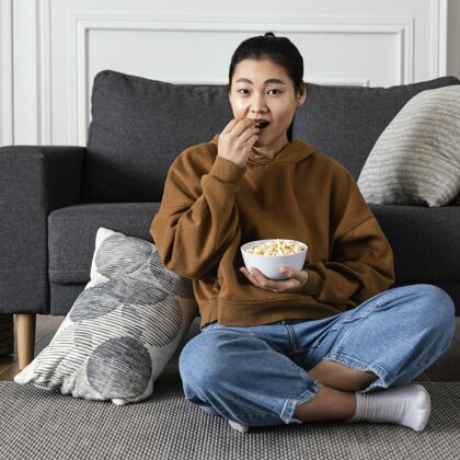 早晨看电视吃爆米花的女人放松室内生活方式