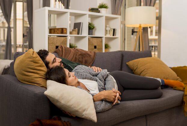 关怀躺在沙发上的一对情侣的侧视图北欧风格海格斯堪的纳维亚风格