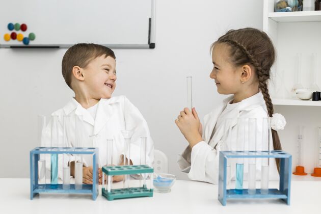 孩子带着试管和实验服的可爱的年轻科学家们实验室男孩科学