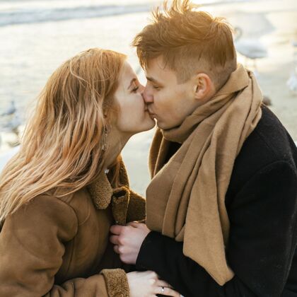 冒险一对情侣在冬天的海滩上亲吻和玩耍的侧视图男人休闲探索