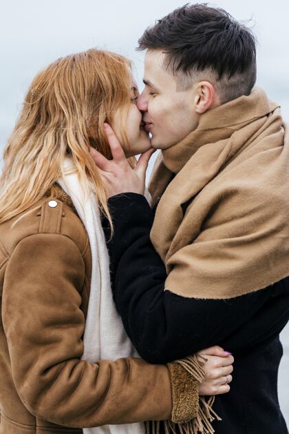 消遣年轻情侣在冬天接吻的侧视图户外户外男人