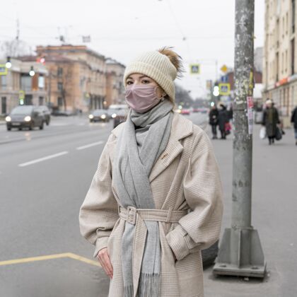 面罩戴着医用口罩的女人在城里等公共汽车人病毒安全