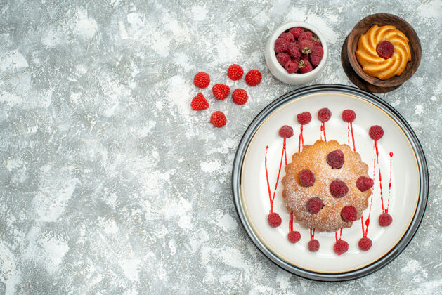 观顶视图浆果蛋糕在白色椭圆形盘子碗与树莓饼干在灰色表面自由空间饼干覆盆子碗