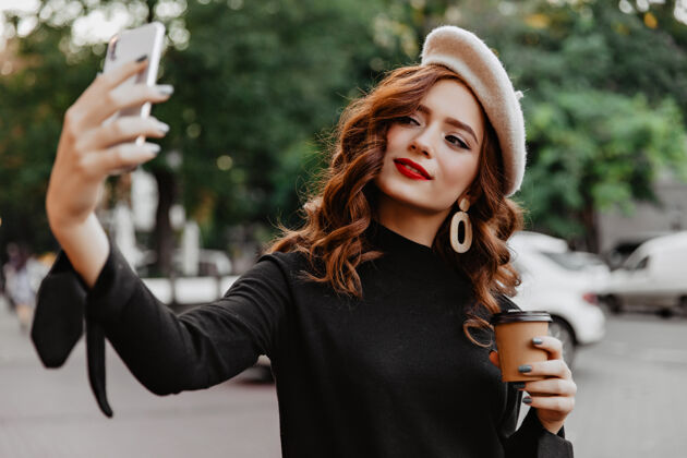 季节对法国贝雷帽感兴趣的女人在11月的早晨摆姿势一杯咖啡的迷人姜模特的户外镜头享受女人肖像