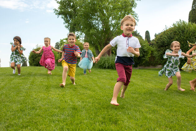 可爱有趣的开始儿童时尚概念一群少年男孩和女孩在公园里跑步阳光童年服饰
