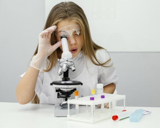 青年年轻的女科学家用显微镜科学女孩教育