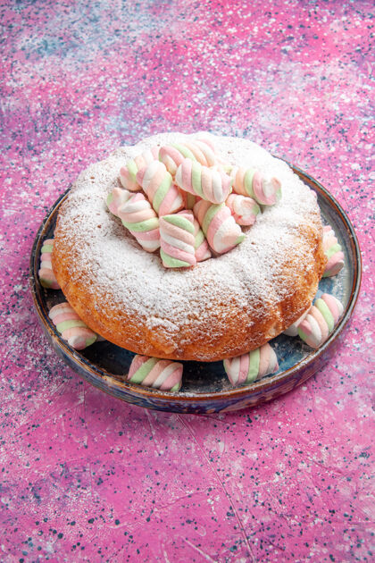糖粉红色墙上糖粉蛋糕和棉花糖的半顶视图百吉饼棉花糖生的
