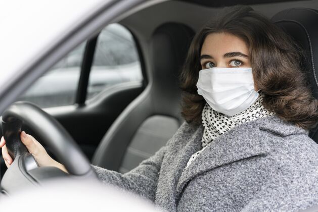 驾驶戴着医用面罩的女士驾驶汽车的侧视图女性面罩个人