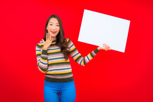 商务女士在红墙上用白色的空广告牌描绘美丽的亚洲年轻女子欢呼年轻人持有
