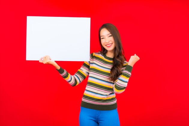 商务女士在红墙上用白色的空广告牌描绘美丽的亚洲年轻女子女性休闲微笑
