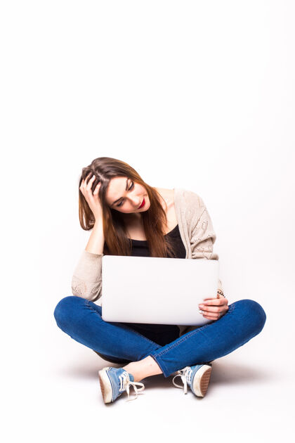 学校一个心烦意乱的女孩穿着背心拿着笔记本电脑坐在白色的地板上笔记本电脑地板年轻