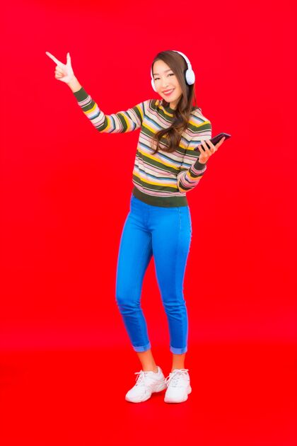 手机肖像美丽的亚洲年轻女子使用智能手机和耳机听音乐乐趣加油科技