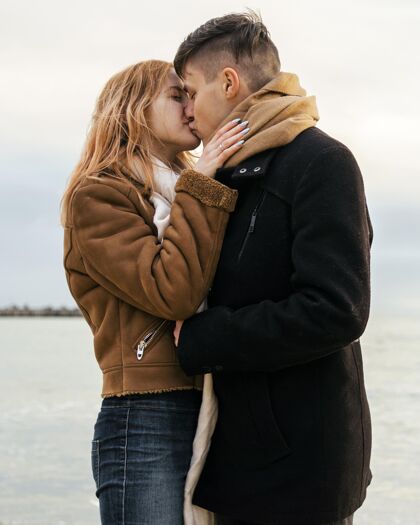 季节可爱的年轻情侣在冬天的海边接吻消遣休闲业余爱好