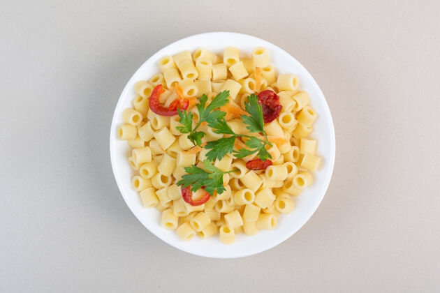面食佩恩意大利面配欧芹和番茄片在白碗里食物美味烹饪