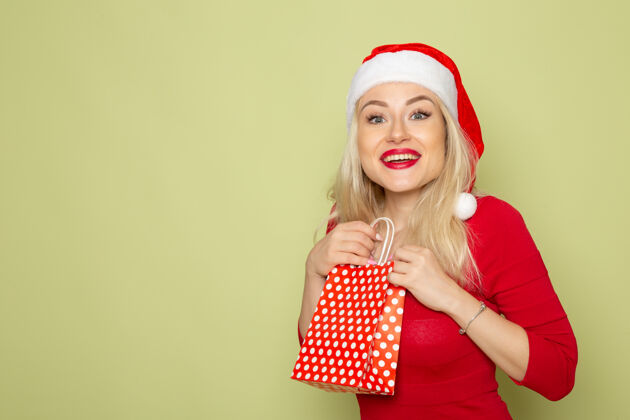 包装正面风景美丽的女性拿着礼物在绿色墙上的小包装情感节日圣诞色新年色彩漂亮小