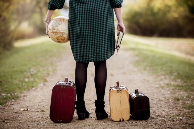 女孩一个女人站在手提箱旁边的空路上 手里拿着圣经和地球仪工作西装成功