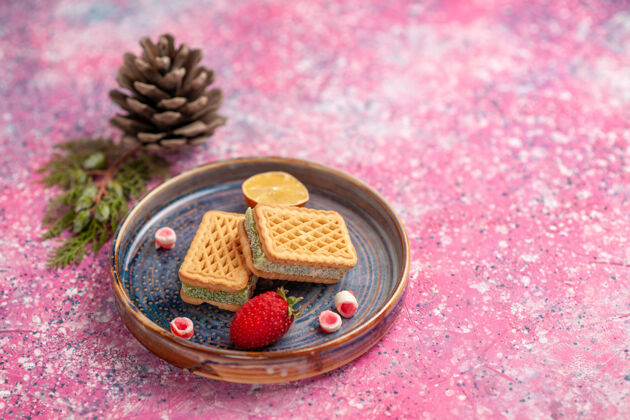 糖粉红色桌子上美味华夫饼的正面图 还有一个草莓食品烘焙生的