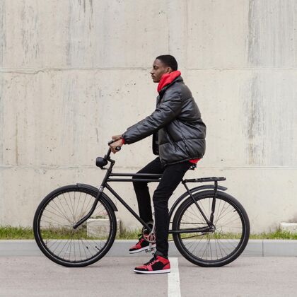 骑美国黑人男子和他的自行车侧视图替代户外城市