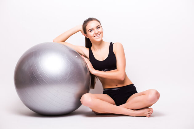 物理一个年轻的女人拿着一个孤立在白墙上的球锻炼私人教练性感运动员