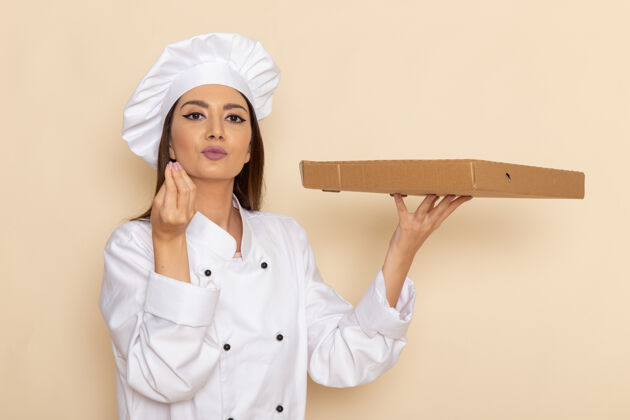 盒子身穿白色厨师服的年轻女厨师正拿着食物盒站在浅白的墙上人女性成人