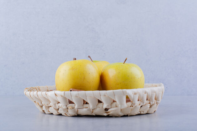 成熟柳条筐的新鲜黄苹果放在石桌上美味有机新鲜