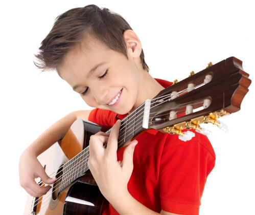 吉他手微笑的白人男孩正在弹原声吉他-孤立在白墙上舞台肖像年轻