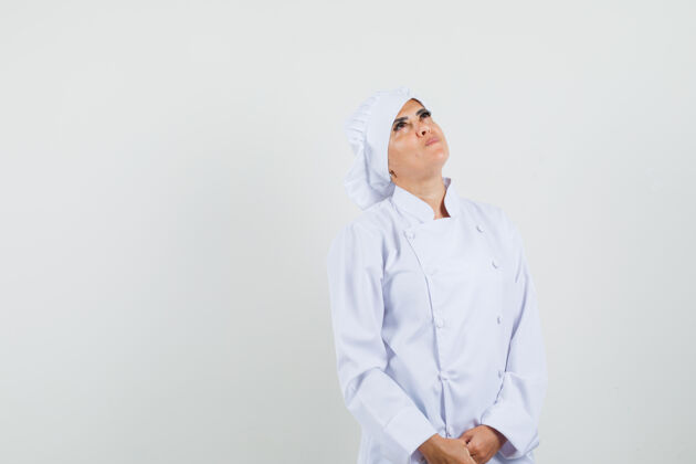 柜台身着白色制服的女厨师抬起头 神情专注工人工作举行