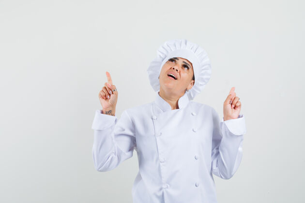 指向一位身穿白色制服的女厨师站起来 看上去充满希望厨师烹饪工业