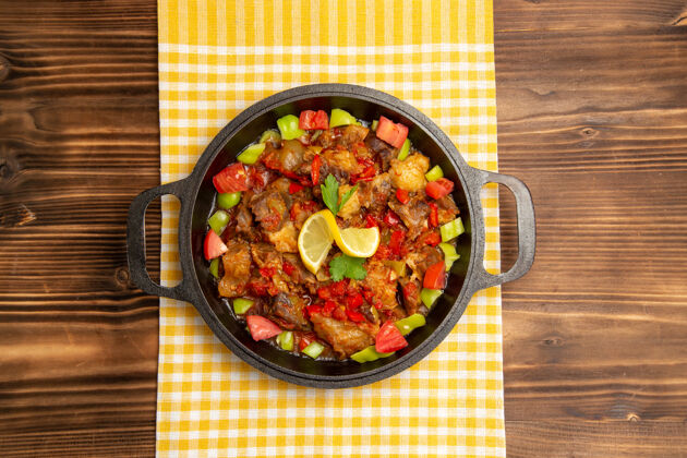肉顶视图煮熟的蔬菜餐 肉和切好的甜椒放在木桌上的平底锅里生的菜甜椒