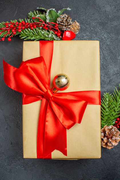 弓垂直视图的圣诞背景与蝴蝶结形彩带和杉木枝装饰配件在一个黑暗的桌子上美丽的礼物轮子弓形树枝