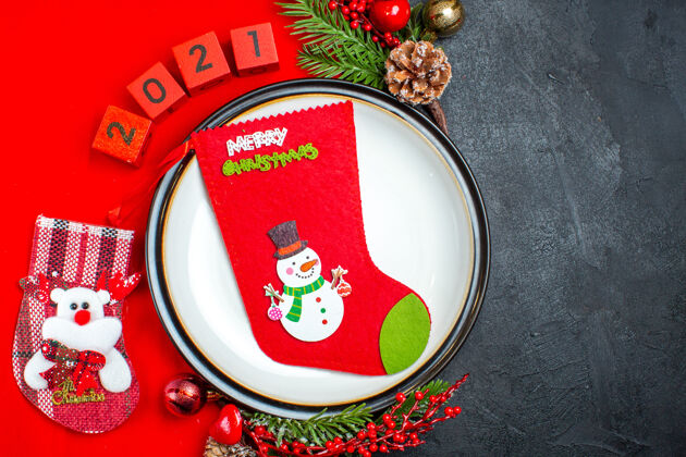 午餐餐盘装饰配件顶视图杉木树枝和数字圣诞袜在黑色背景上的红色餐巾上餐巾号码顶