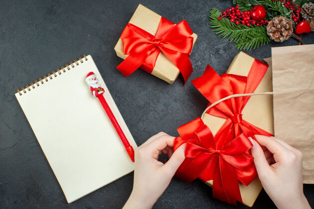心情上图是圣诞气氛 有漂亮的礼物和红丝带 黑色背景上有钢笔的笔记本圣诞节轮子风景