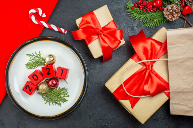 包装上图装饰配件数在一个盘子上 精美礼品冷杉枝针叶树锥在一张深色的桌子上蝴蝶结圣诞冷杉