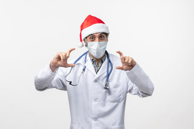 男医生正面图白色墙壁上戴着口罩的男医生大流行的柯维德假日病毒视图制服医生