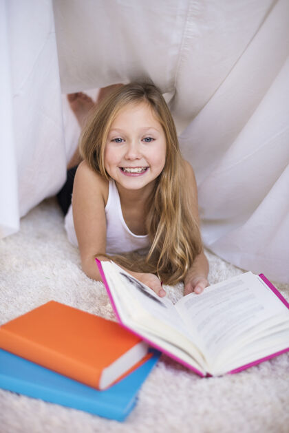 创意快乐的女孩在一个手工棚子里看书向上无辜检查