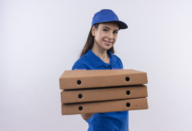 女孩身穿蓝色制服 戴着帽子的年轻送货员拿着一叠比萨饼盒 面带自信的微笑看着镜头站着年轻帽子