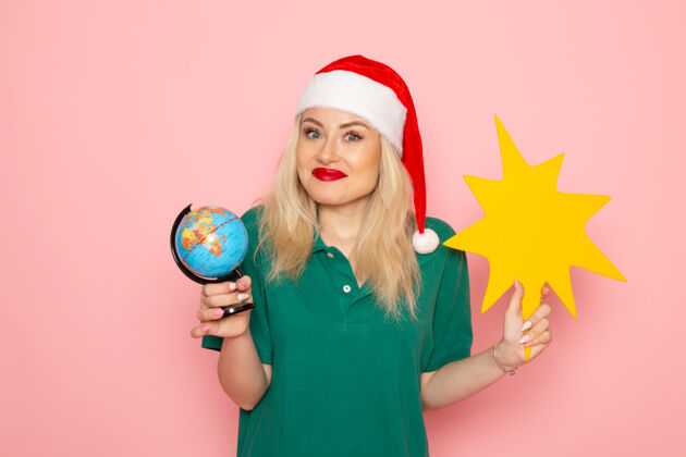 地球仪正面图年轻女性手持地球仪和黄色人像在粉色墙壁上模特女性圣诞假期照片新年色彩身材颜色巫师