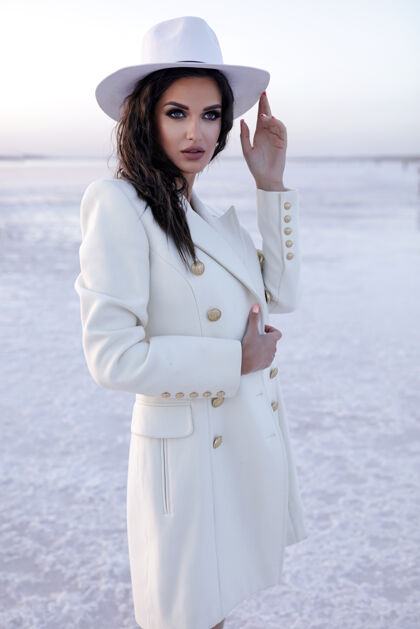 积极穿着冬天鞋子的白衣女人穿着外套的欧洲女孩在寒冷的日子里微笑快乐的金发女人在冬天玩照片拍摄冬天的湖在雪温暖的靴子帽子Swoosh漂亮波浪发