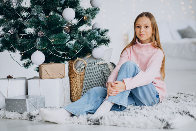 灯坐在圣诞树旁的小女孩女孩装饰明亮