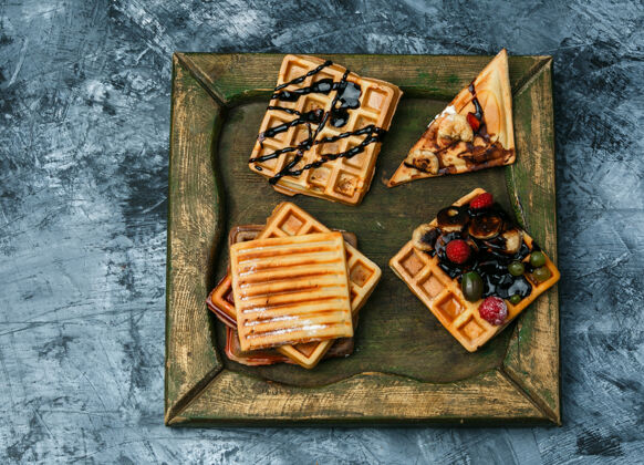 青铜不同的华夫饼放在深蓝色大理石背景的铜板上顶视图鸡蛋冰木头